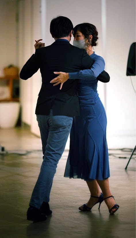 男性と女性が手を取り合い、寄り添いながら、タンゴのダンスをペアで踊っている全身写真