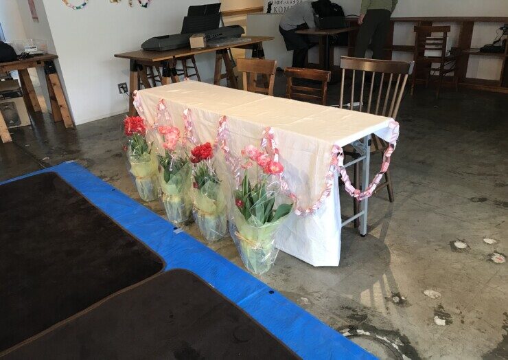 小学校の学童の卒業式のメインテーブルの前に、花束が並べられている光景
