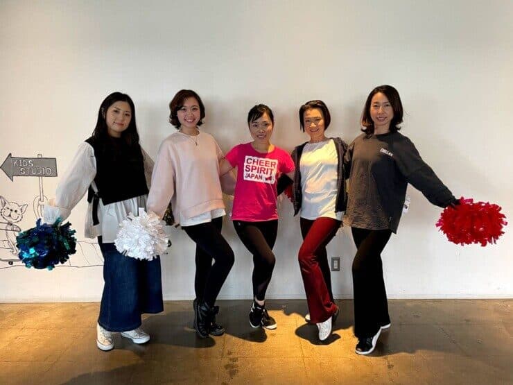 チアダンススクールのプロフィール写真撮影にて、皆さんがボンボンを持ち、白い壁の前にて立っている光景